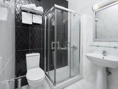 Bagno moderno con doccia, WC, lavandino e asciugamani in design elegante.