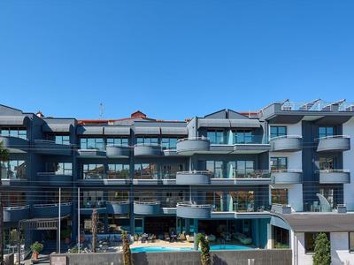 Hotel moderno con balconi e piscina sotto un cielo azzurro limpido.