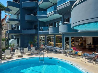 Piscina moderna dell'hotel circondata da lettini e balconi in un edificio su più piani.