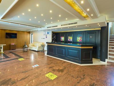Una hall d'hotel moderna con reception, divani e scale per il piano superiore.