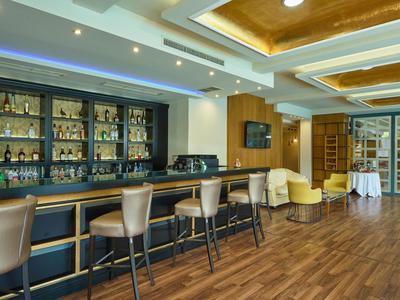 Area bar di un hotel moderno con scaffali illuminati, sgabelli e poltrone accoglienti.