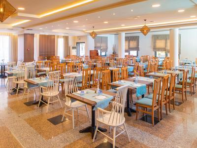Ristorante luminoso e moderno con mobili in legno, tavoli apparecchiati e luci a soffitto.