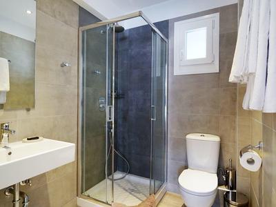 Moderne badkamer met douche, toilet en wastafel in neutrale tinten.