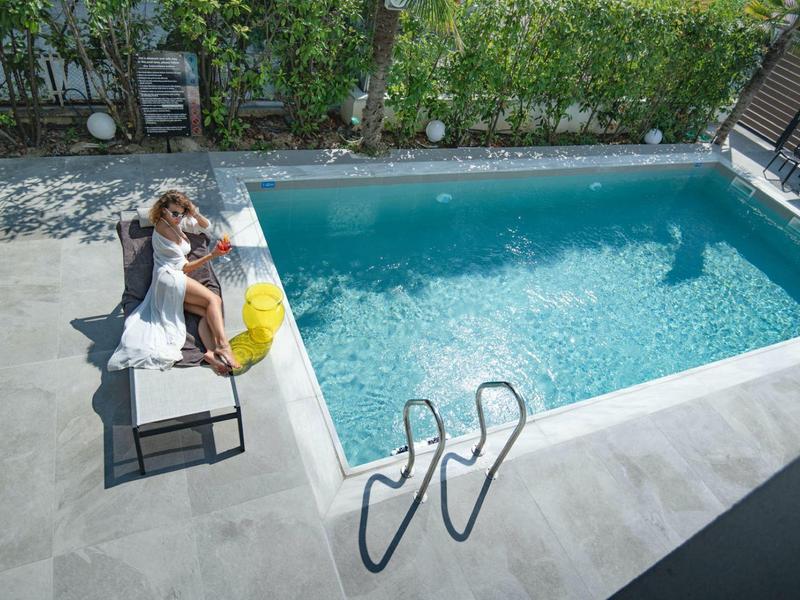 Vrouw met boodschappentas zittend op bank naast helder zwembad op zonnige dag