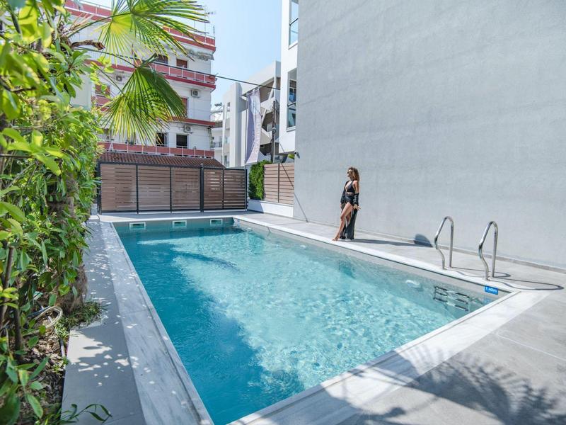 Modern buitenzwembad naast een hotelgebouw met een persoon aan de rand van het zwembad.