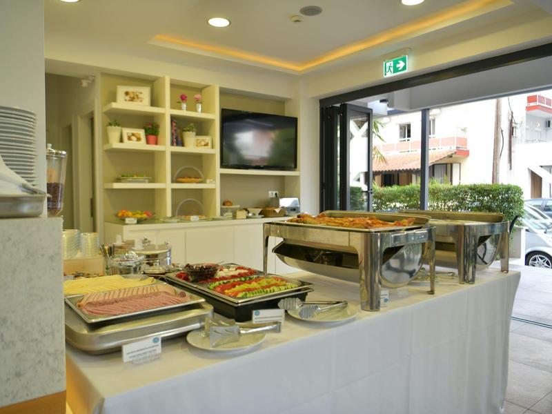 Buffet met warme en koude gerechten in een modern hotelrestaurant naast een glazen wand.