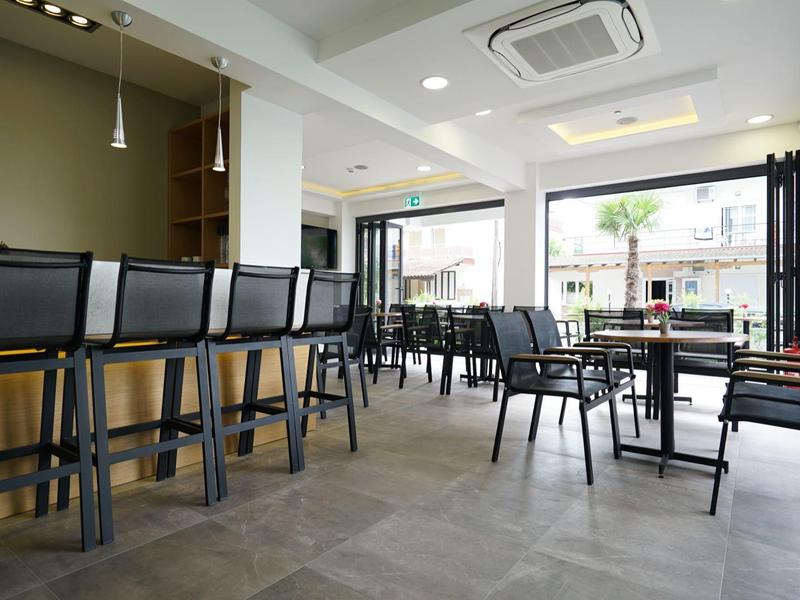 Modern hotelrestaurant met donkere stoelen en grote ramen voor veel daglicht.