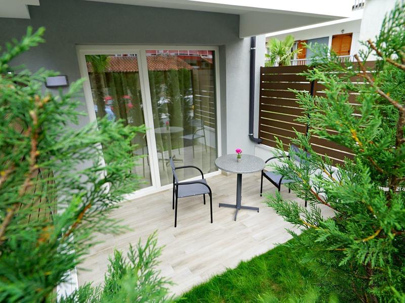 Terras met stoelen en tafel omringd door groene planten voor een hotelkamer.