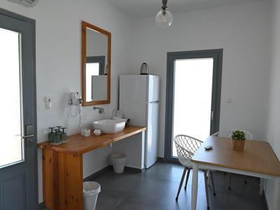 Habitación moderna y luminosa con mueble de madera, espejo, nevera, mesa y sillas.