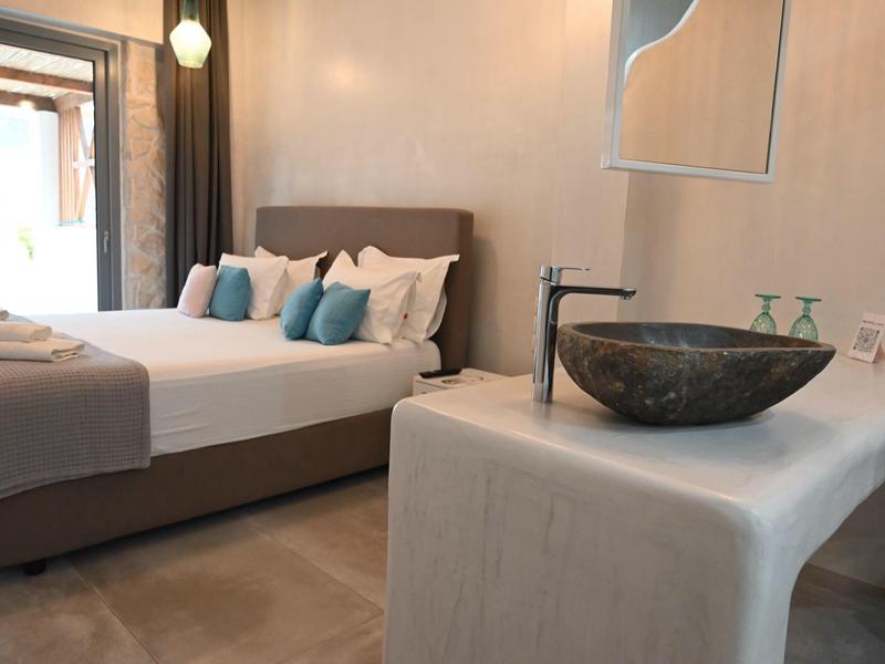 Habitación de hotel moderna con cama doble, almohadas y lavabo integrado en primer plano.