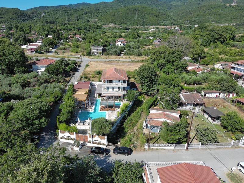 Vista aérea de un hotel con piscina rodeado de paisaje verde y montañas.