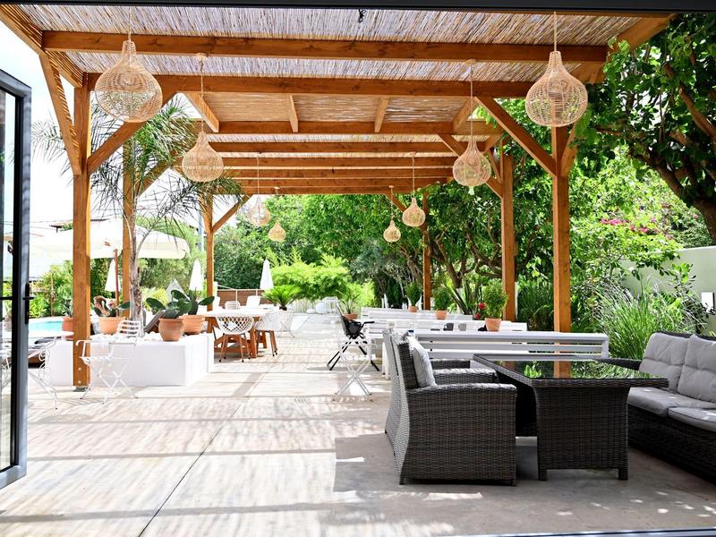 Terraza cubierta con zona de estar y vista al jardín en un hotel o casa de vacaciones.