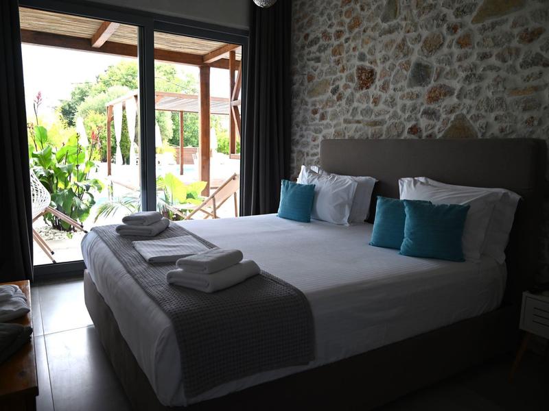 Acogedor dormitorio con cama grande, cojines azules y vista a una terraza.