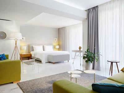 Nowoczesny pokój hotelowy z łóżkiem, miejscem do siedzenia i dużymi oknami z zasłonami.