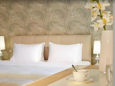 Jasno urządzony pokój hotelowy z łóżkiem podwójnym, lampkami nocnymi i dekoracyjną tapetą