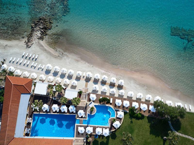 Widok z lotu ptaka na plażę z leżakami i dwoma basenami obok hotelu