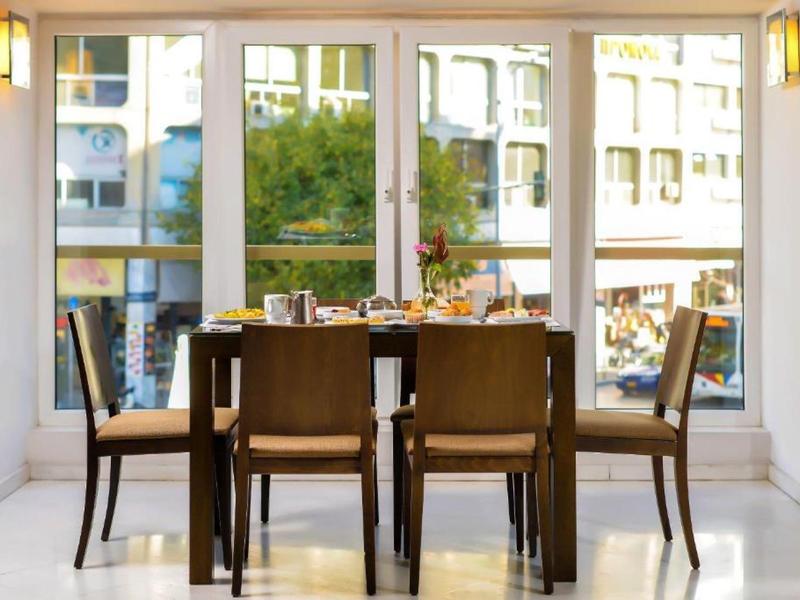Area pranzo con cinque sedie davanti a grandi finestre con vista su un edificio urbano