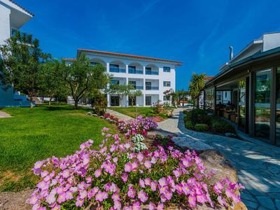 Fiori in fiore in un giardino davanti a un edificio moderno di un hotel in una giornata di sole.
