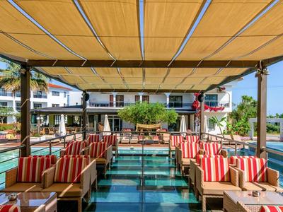 Ristorante all'aperto con aree salotto confortevoli con vista sull'acqua e sugli edifici dell'hotel.
