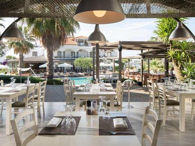 Posti a sedere all'aperto di un ristorante con vista su piscina e palme in un resort.