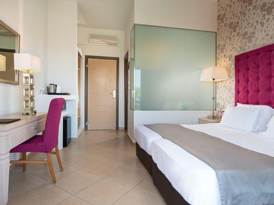 Modern hotel room with large bed, desk, chair, and open bathroom area.