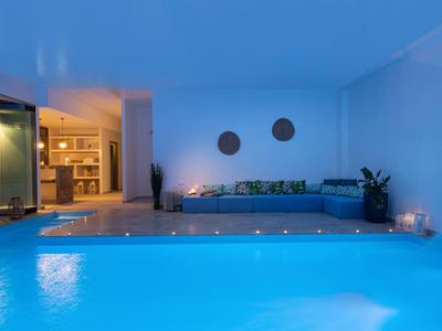 Piscina interna moderna con acqua blu e zona salotto accogliente in una stanza elegante