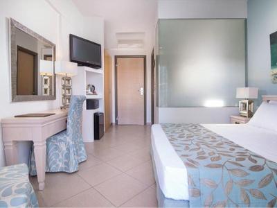 Camera d'hotel luminosa con letto matrimoniale, scrivania, TV e arredi moderni.