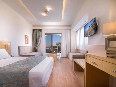 Camera d'hotel moderna con letto grande, scrivania e balcone con vista sul mare.