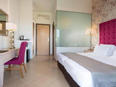 Camera d'hotel moderna con letto grande, sedia rossa e scrivania vicino all'ingresso.