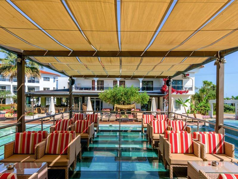 Ristorante all'aperto con aree salotto confortevoli con vista sull'acqua e sugli edifici dell'hotel.