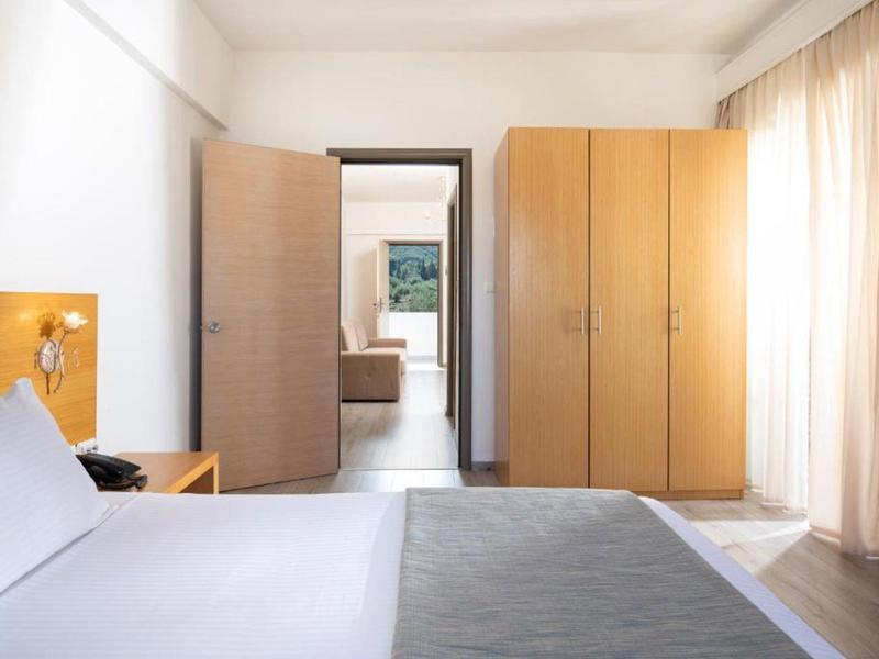 Camera d'hotel luminosa arredata con letto, armadio e balcone con tenda.