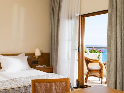 Pokój hotelowy z łóżkiem, lampką nocną i balkonem z widokiem na morze