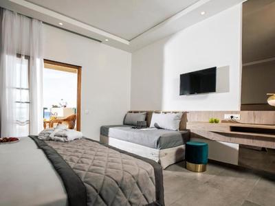 Nowoczesny pokój hotelowy z podwójnym łóżkiem, sofą, telewizorem na ścianie i biurkiem z krzesłem.