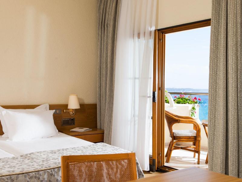 Pokój hotelowy z łóżkiem, lampką nocną i balkonem z widokiem na morze