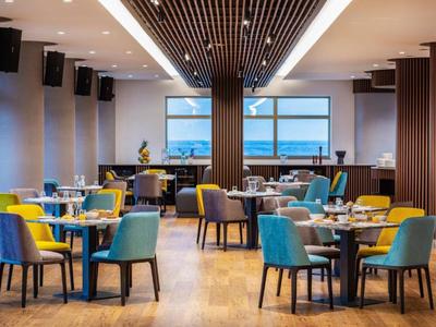 Modern restaurant with colorful chairs and wooden floors overlooking the sea