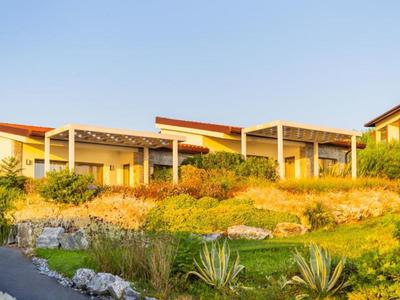 Modern hotel complex with bungalows surrounded by greenery and blue sky.
