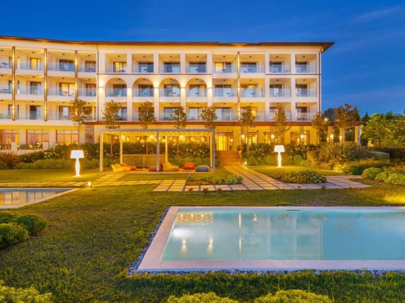 Modern hotel at sunset with illuminated pool and well-kept garden