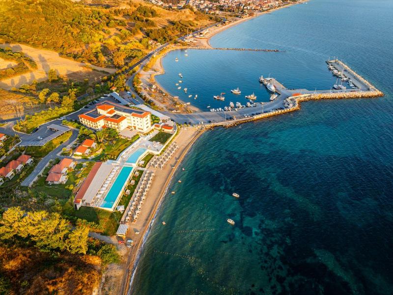 Aerial view of a resort with pools, beach, and marina along the coast.