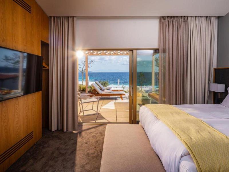 Modern hotel room with sea view and terrace with sun umbrellas.