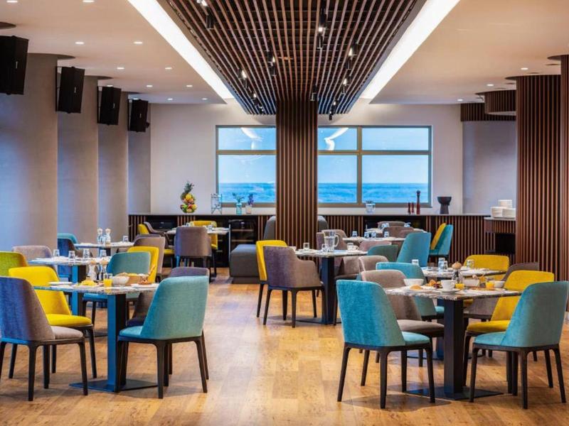 Modern restaurant with colorful chairs and wooden floors overlooking the sea