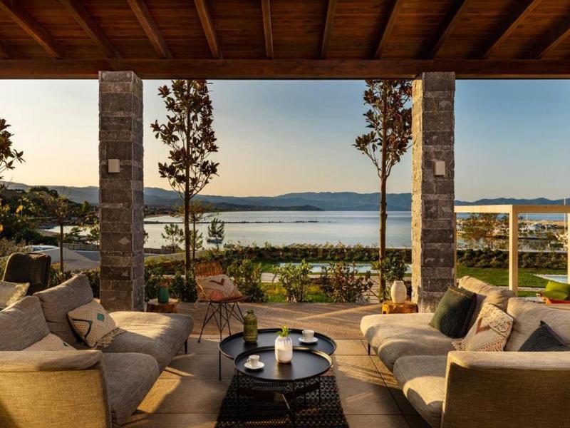 Cozy lounge with sofas and lake view under a wooden roof.