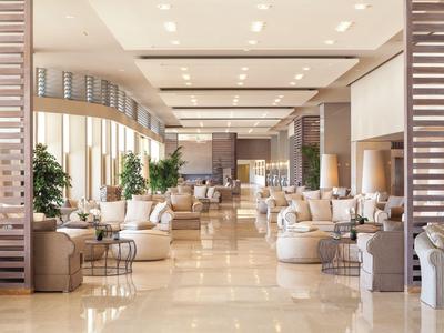 Lichte, moderne hotellobby met comfortabele stoelen, tafels, planten en ruime indeling.