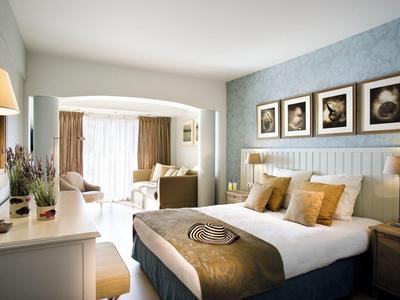 Elegante camera d'hotel con letto grande, poltrone comode e luce naturale da grandi finestre.