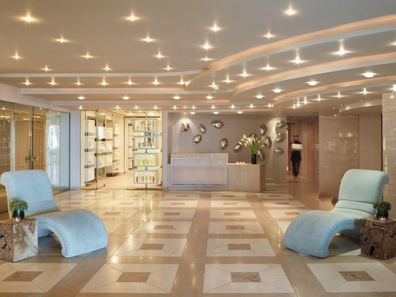 Ampia hall dell'hotel con pavimento in marmo chiaro e sedute moderne blu.