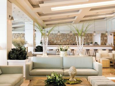 Moderne hotel lounge met witte banken en groene plantendecoraties.