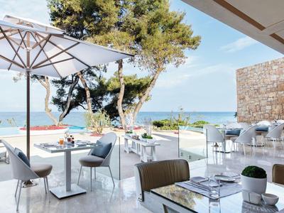 Moderne Terrasse mit Stühlen, Tischen und Sonnenschirmen mit Blick auf das Meer.