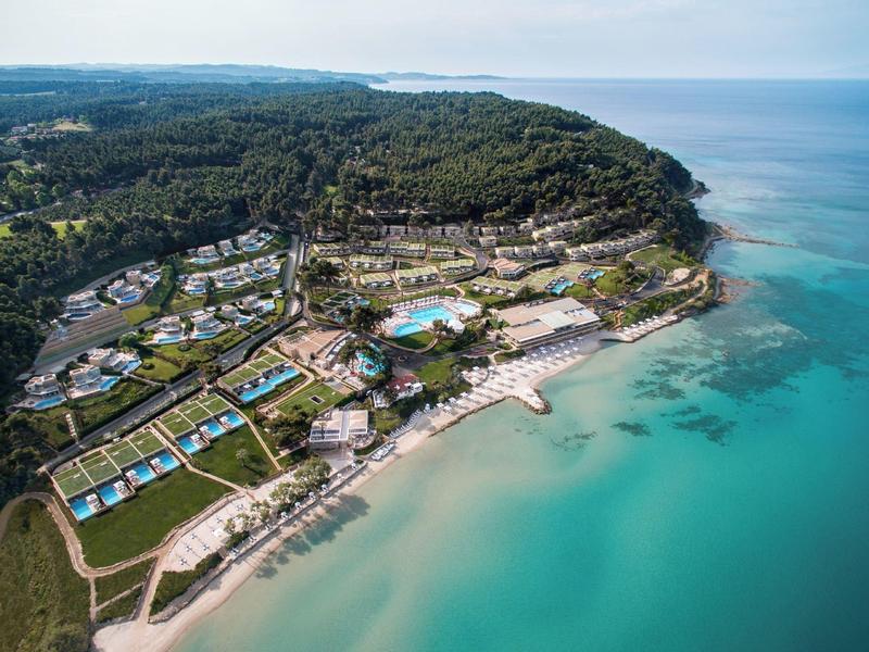 Letecký pohled na resort s bazénem, pláží a obklopený lesem u čistého moře.