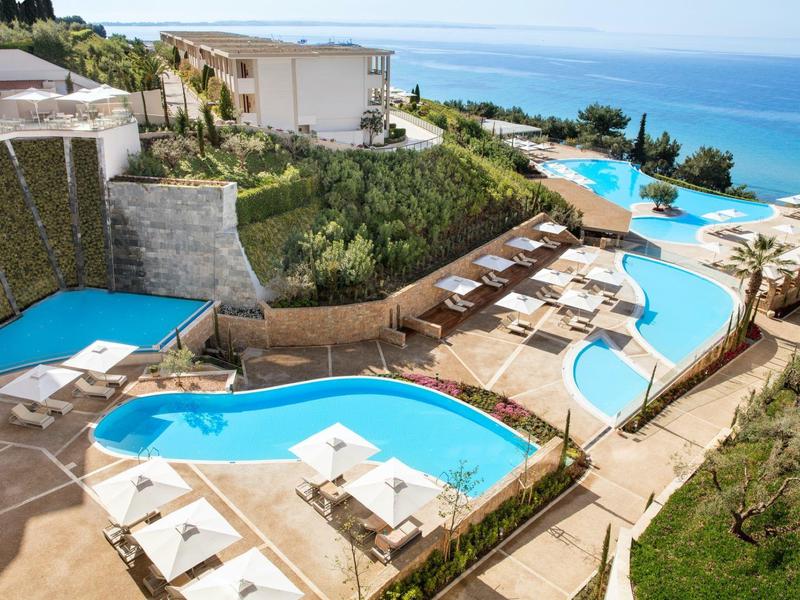 Diverse piscine a laguna con sdraio e vista mare in un complesso alberghiero