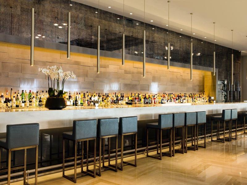 Bar dell'hotel moderna con sgabelli alti e illuminazione decorativa.