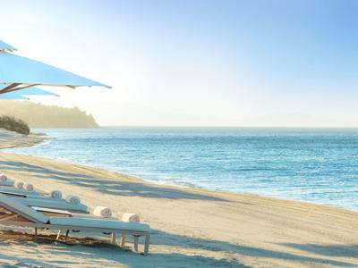 Leerer Strand mit Liegestühlen und Sonnenschirm bei klarem Himmel